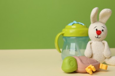 Baby toys and bottle on beige table. Space for text