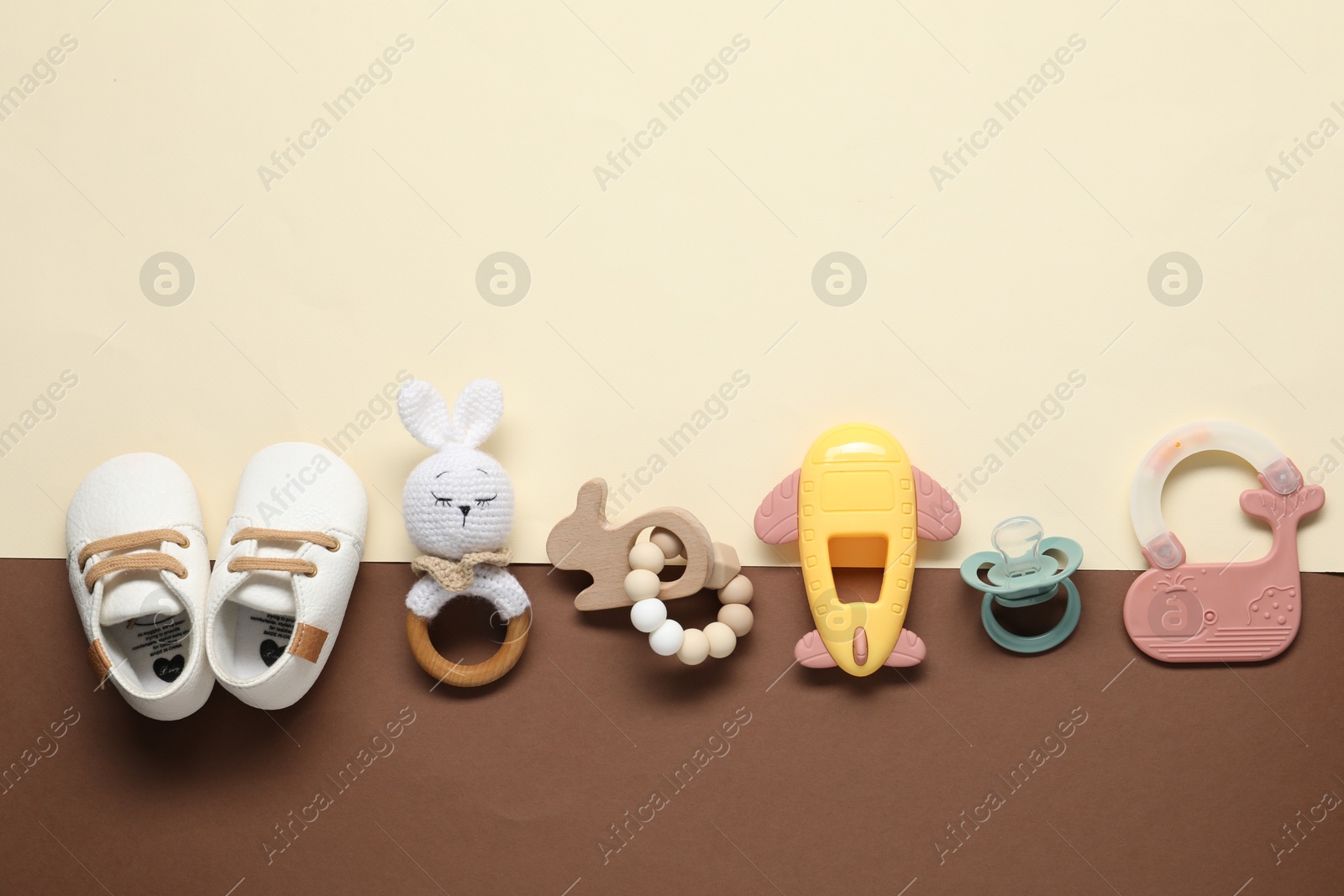 Photo of Different baby rattles and booties on color background, flat lay. Space for text