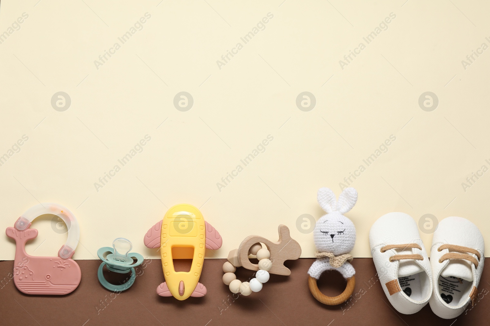 Photo of Different baby rattles and booties on color background, flat lay. Space for text