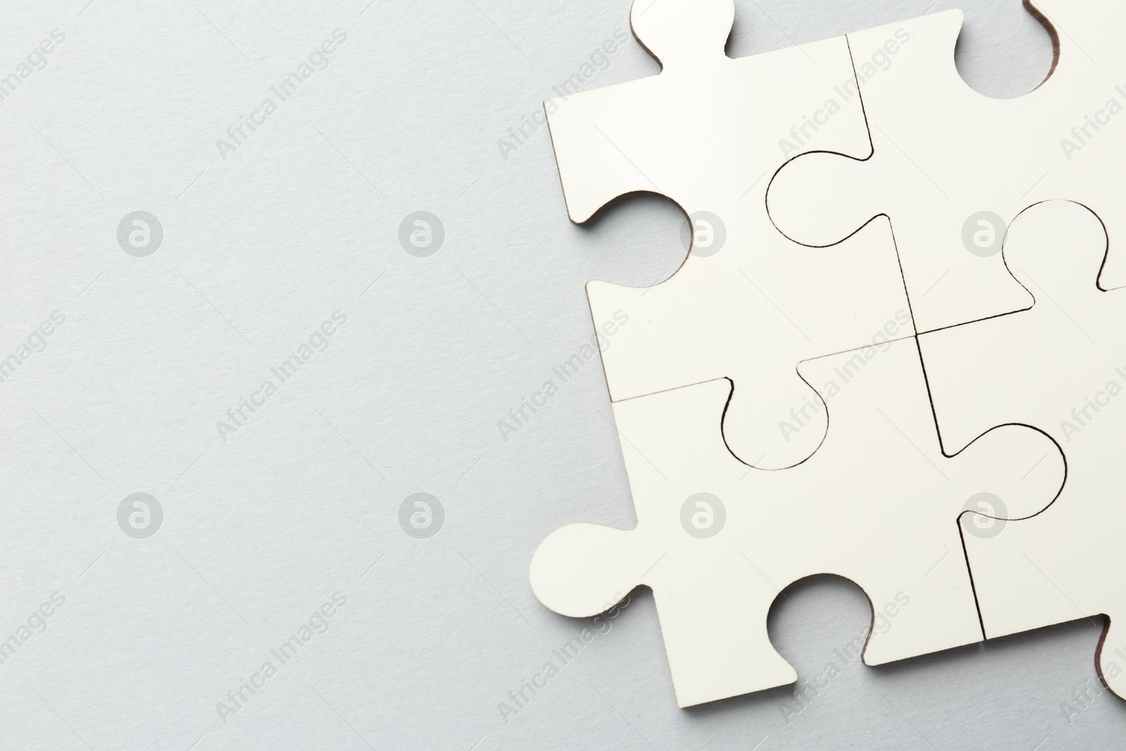 Photo of White puzzle pieces on grey background, top view. Space for text