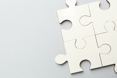 Photo of White puzzle pieces on grey background, top view. Space for text