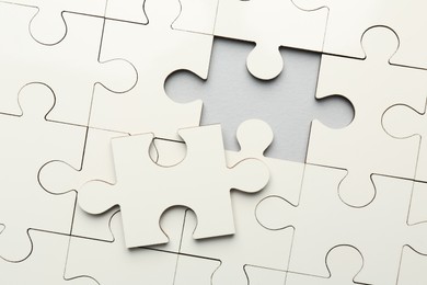 Photo of White puzzle with missing piece on grey background, top view