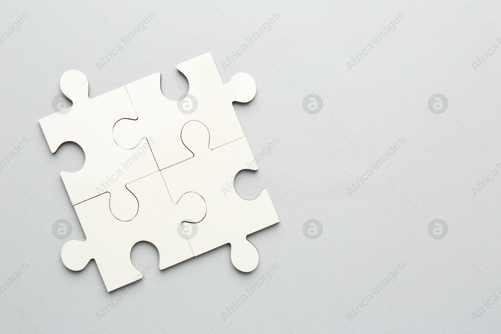 Photo of White puzzle pieces on grey background, top view. Space for text