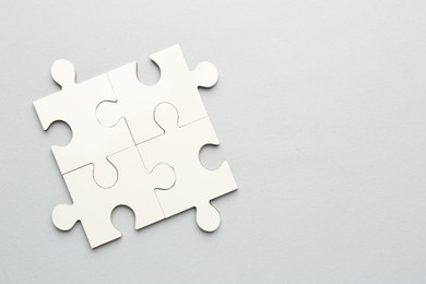 White puzzle pieces on grey background, top view. Space for text