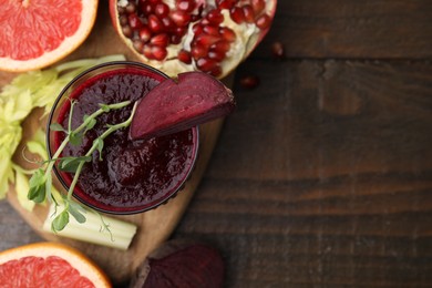 Tasty beetroot smoothie in glass, microgreens, fresh vegetables and fruits on wooden table, top view with space for text. Vegan drink