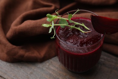 Tasty beetroot smoothie with microgreens in glass on wooden table, closeup. Vegan drink