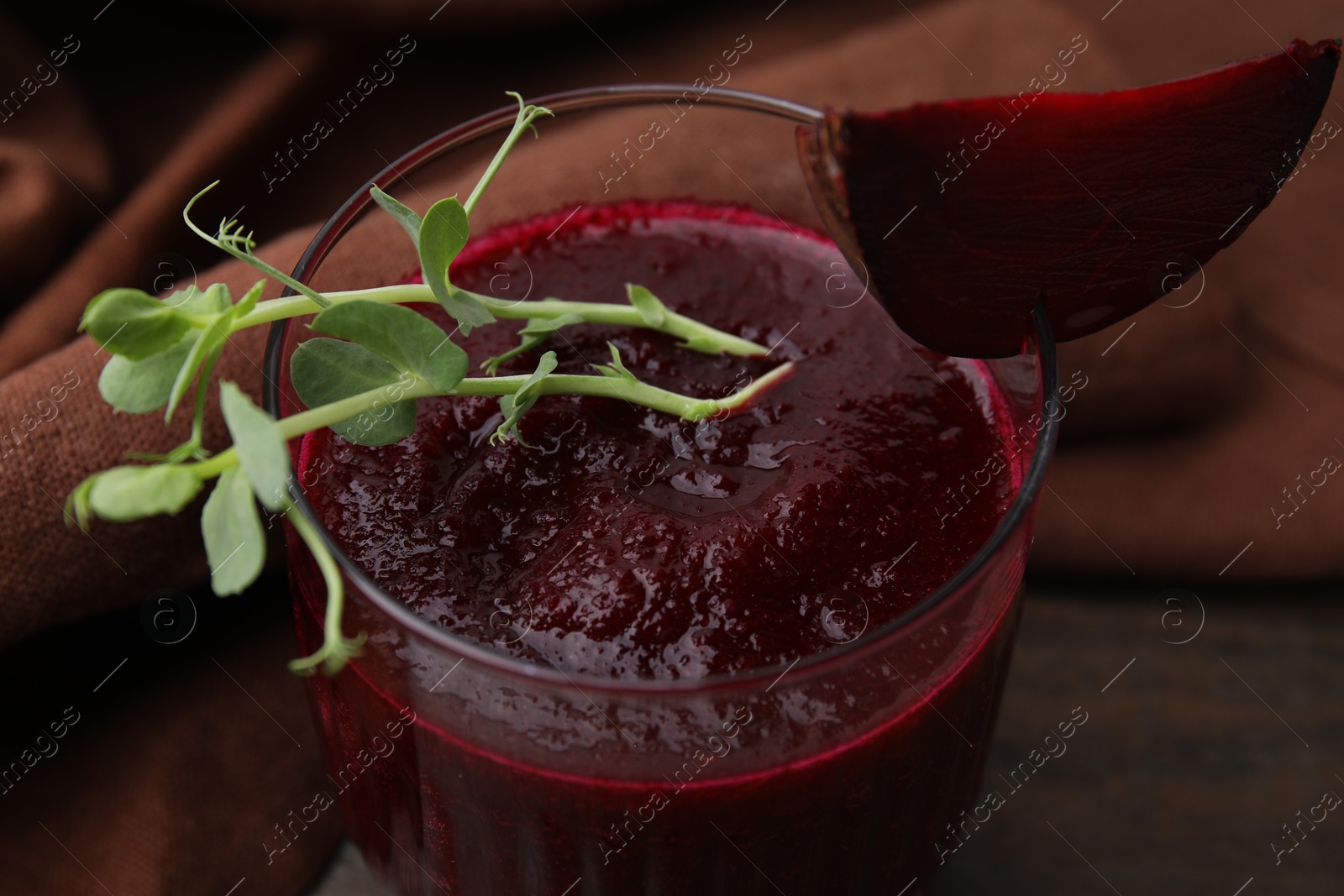 Photo of Tasty beetroot smoothie with microgreens in glass on table, closeup. Vegan drink