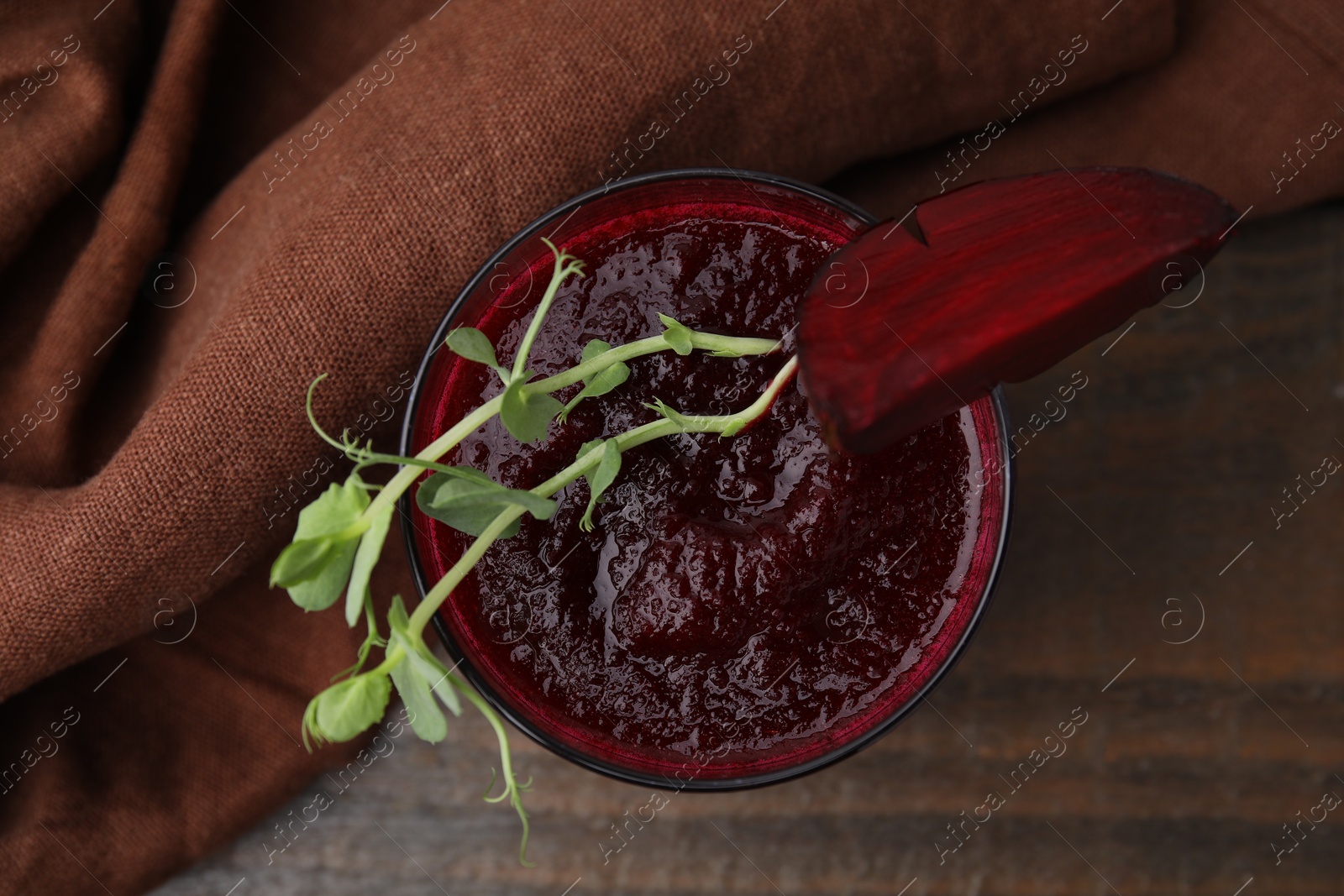 Photo of Tasty beetroot smoothie with microgreens in glass on wooden table, top view. Vegan drink