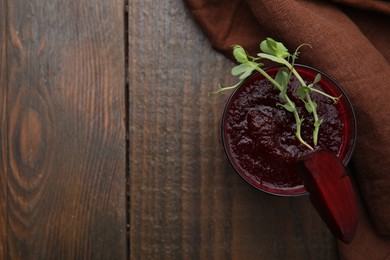 Photo of Tasty beetroot smoothie with microgreens in glass on wooden table, top view and space for text. Vegan drink