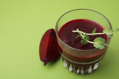 Photo of Vegan drink. Tasty beetroot smoothie with microgreens in glass on green table, closeup. Space for text