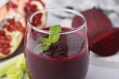 Photo of Tasty beetroot smoothie with mint in glass on table, closeup. Vegan drink