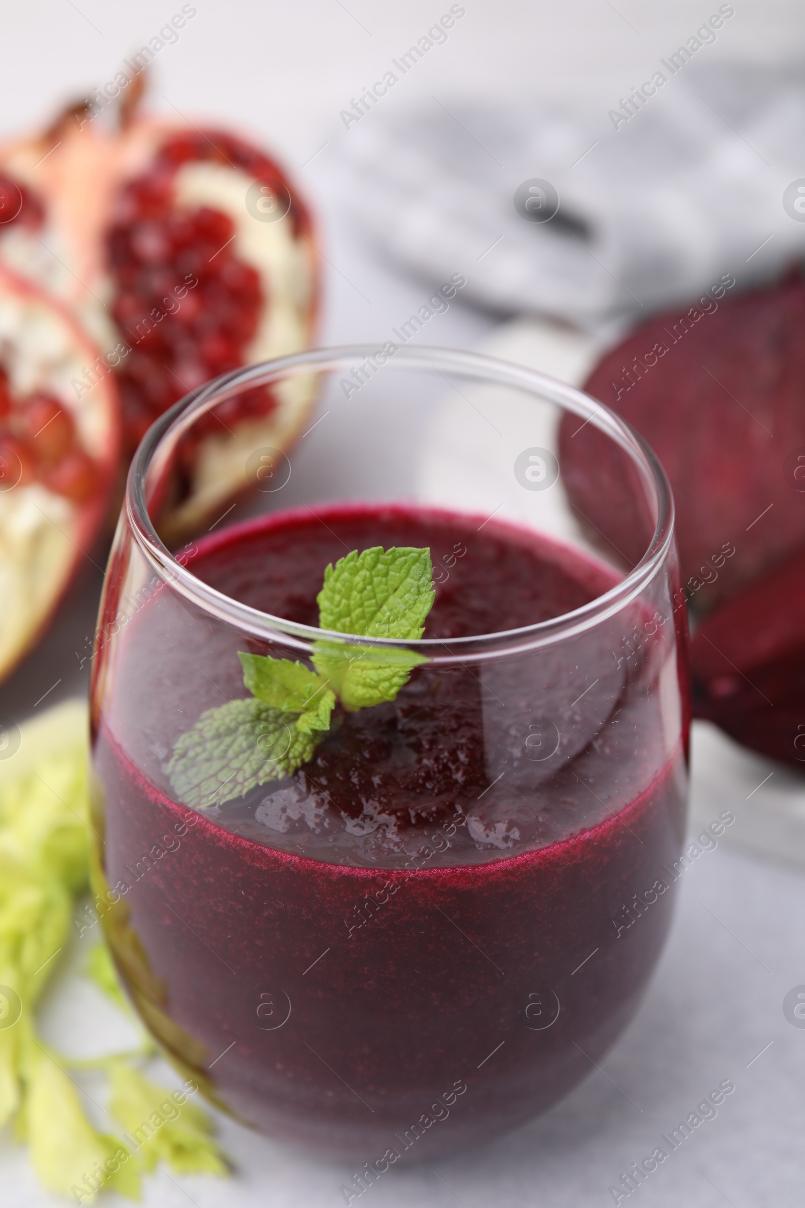 Photo of Tasty beetroot smoothie with mint in glass o light table, closeup. Vegan drink