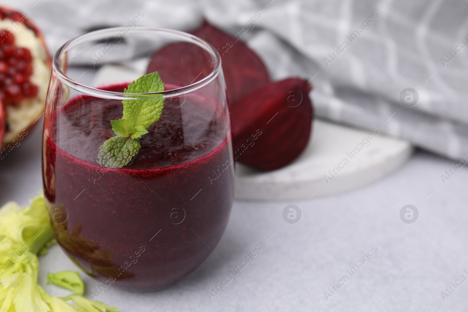 Photo of Vegan drink. Tasty beetroot smoothie in glass and fresh vegetables on light table, closeup. Space for text.