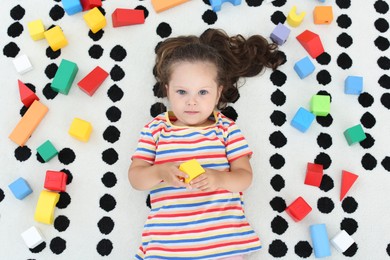 Cute little girl and toys on floor, top view