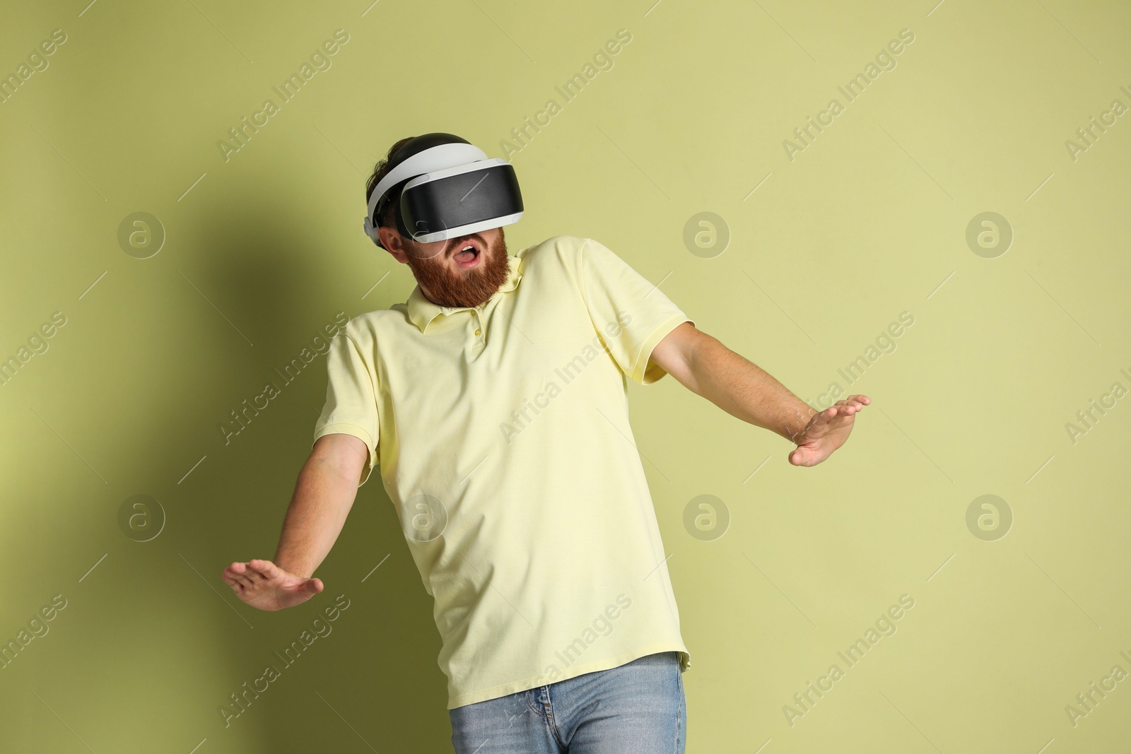 Photo of Emotional man using virtual reality headset on pale green background