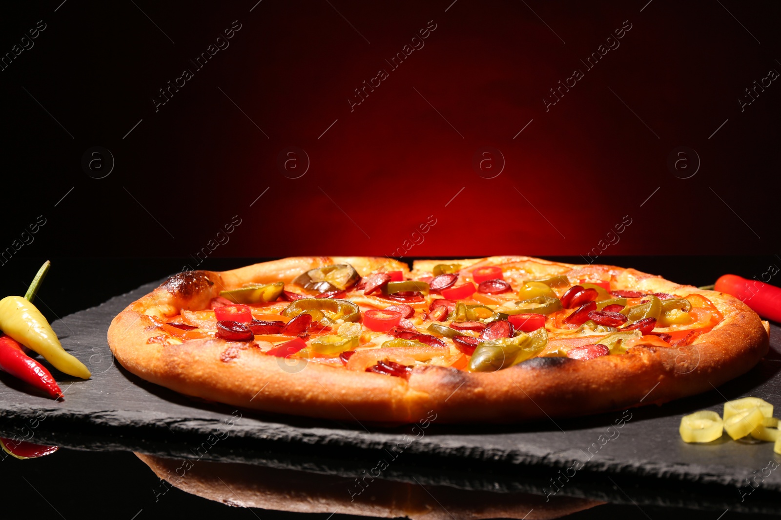 Photo of Delicious pizza Diablo on slate board against red background