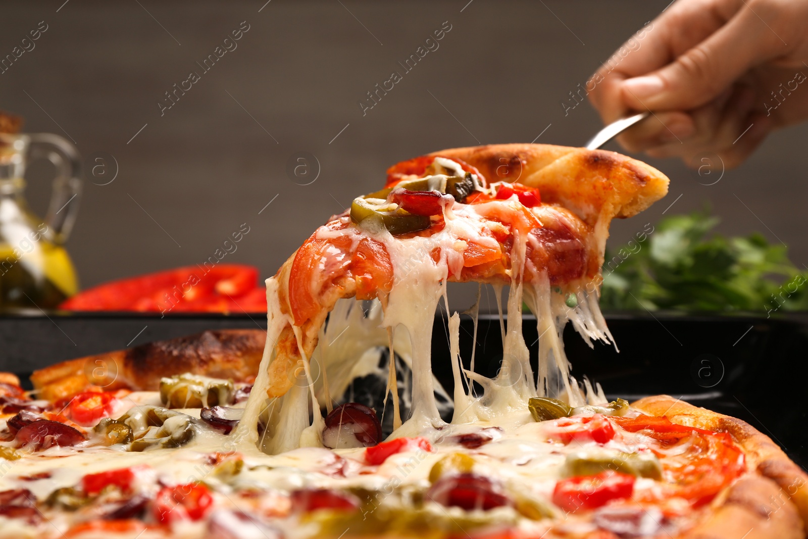 Photo of Woman taking piece of delicious pizza Diablo from baking tray, closeup