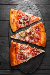 Photo of Board with pieces of delicious pizza Diablo on black wooden table, top view