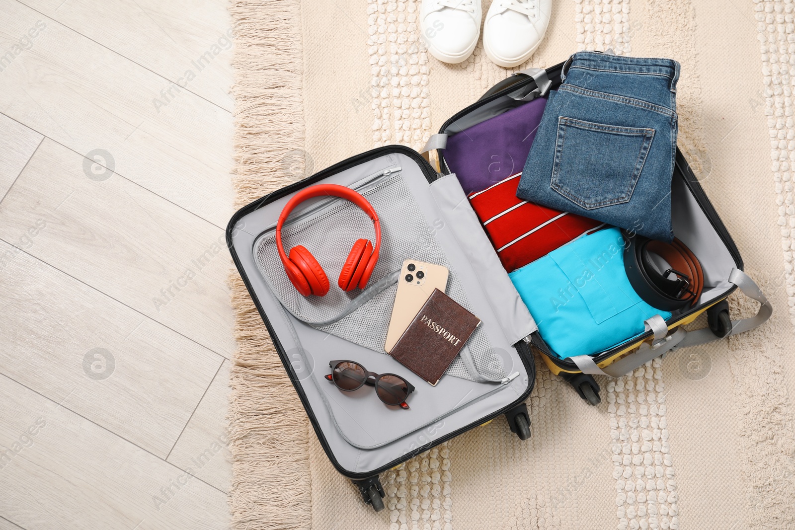 Photo of Open suitcase with traveler's belongings on floor, flat lay. Space for text