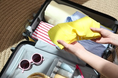 Photo of Woman packing suitcase for trip at home, closeup