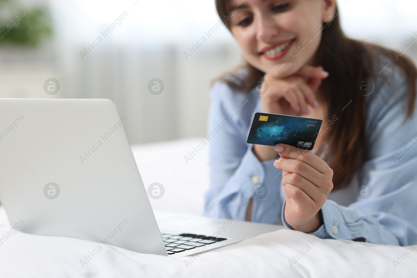 Photo of Online banking. Smiling woman with credit card and laptop paying purchase at home, selective focus