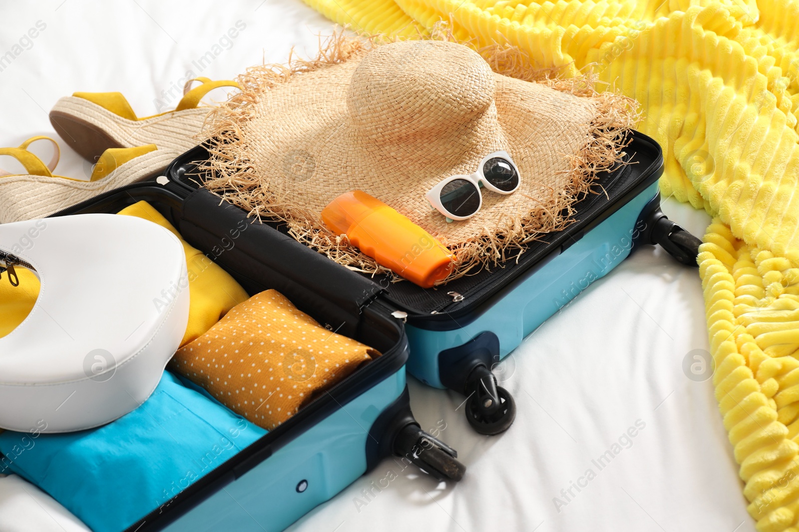 Photo of Open suitcase with traveler's belongings on bed, closeup