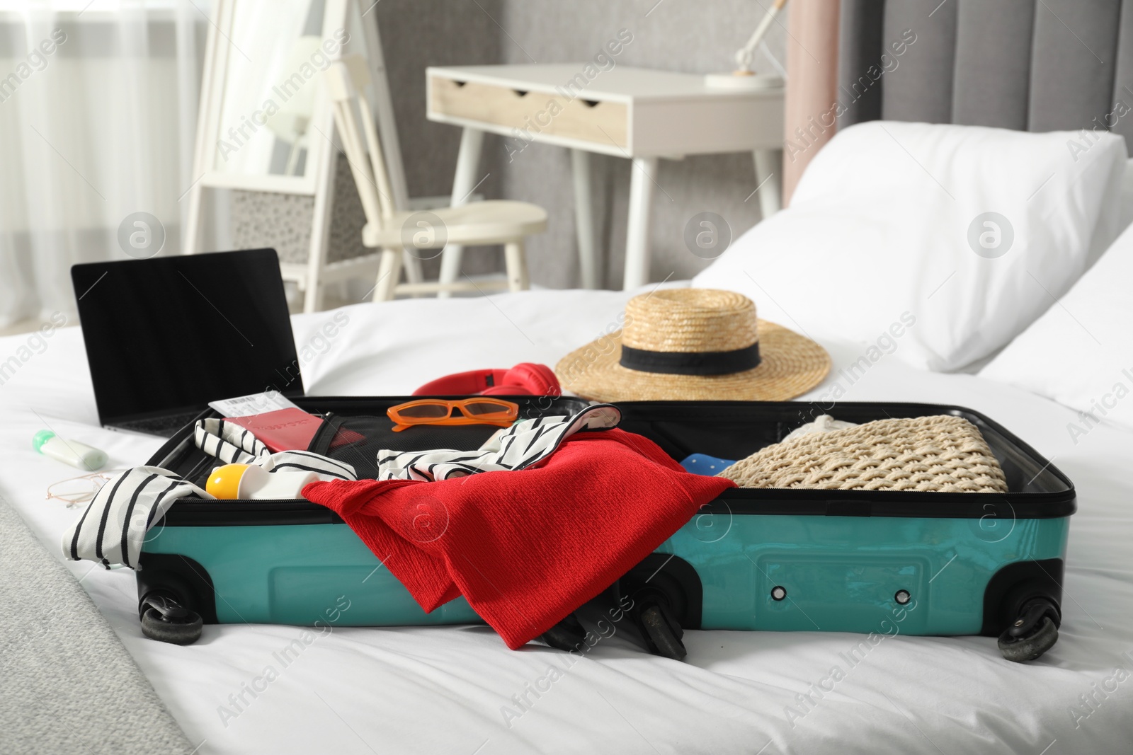 Photo of Open suitcase with traveler's belongings on bed