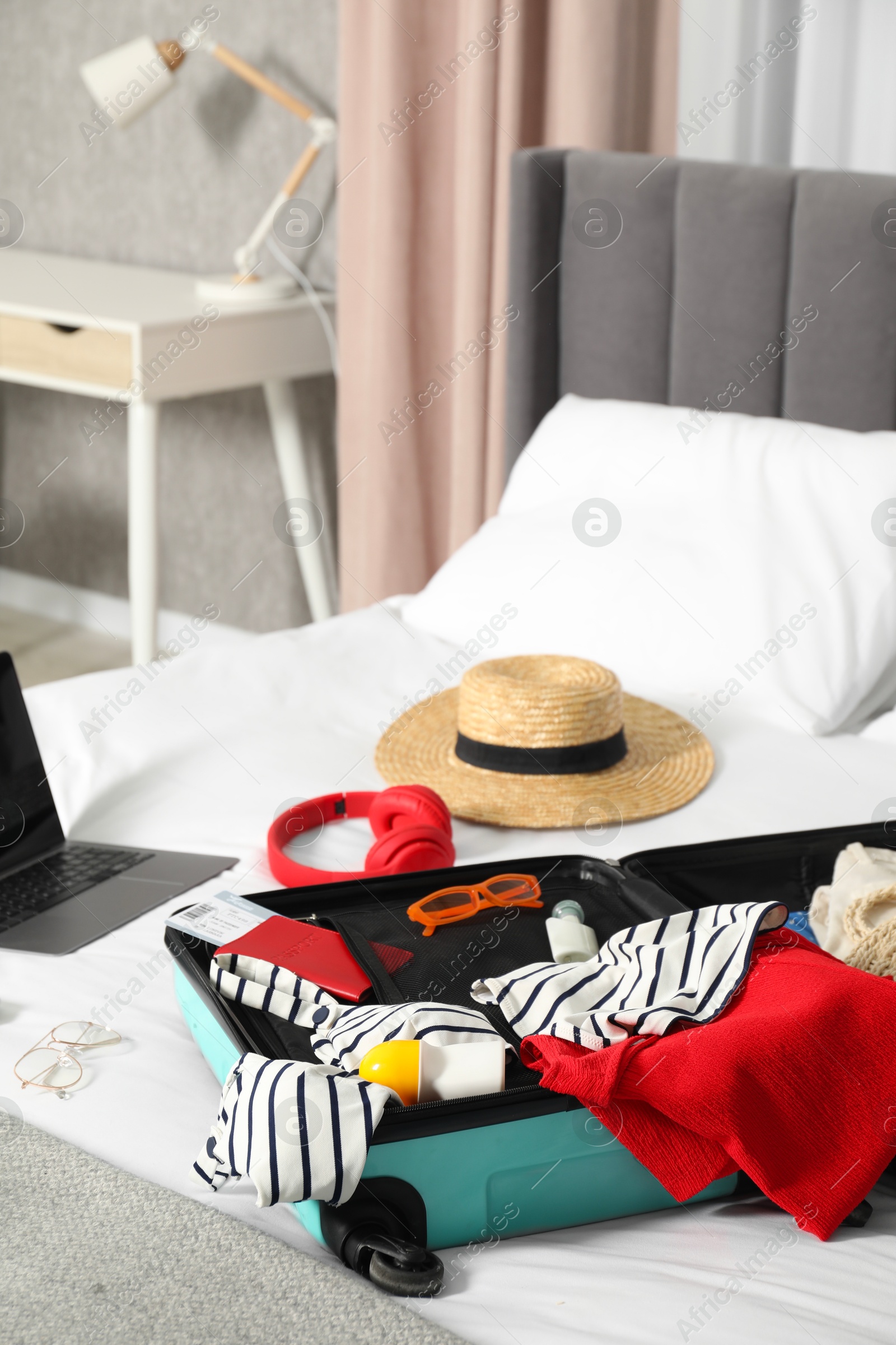 Photo of Open suitcase with traveler's belongings on bed