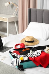 Photo of Open suitcase with traveler's belongings on bed