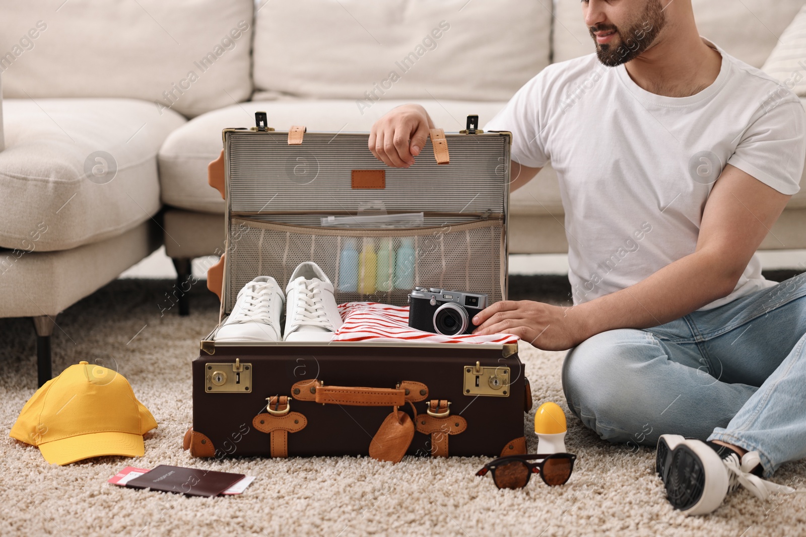 Photo of Man packing suitcase on floor at home, closeup