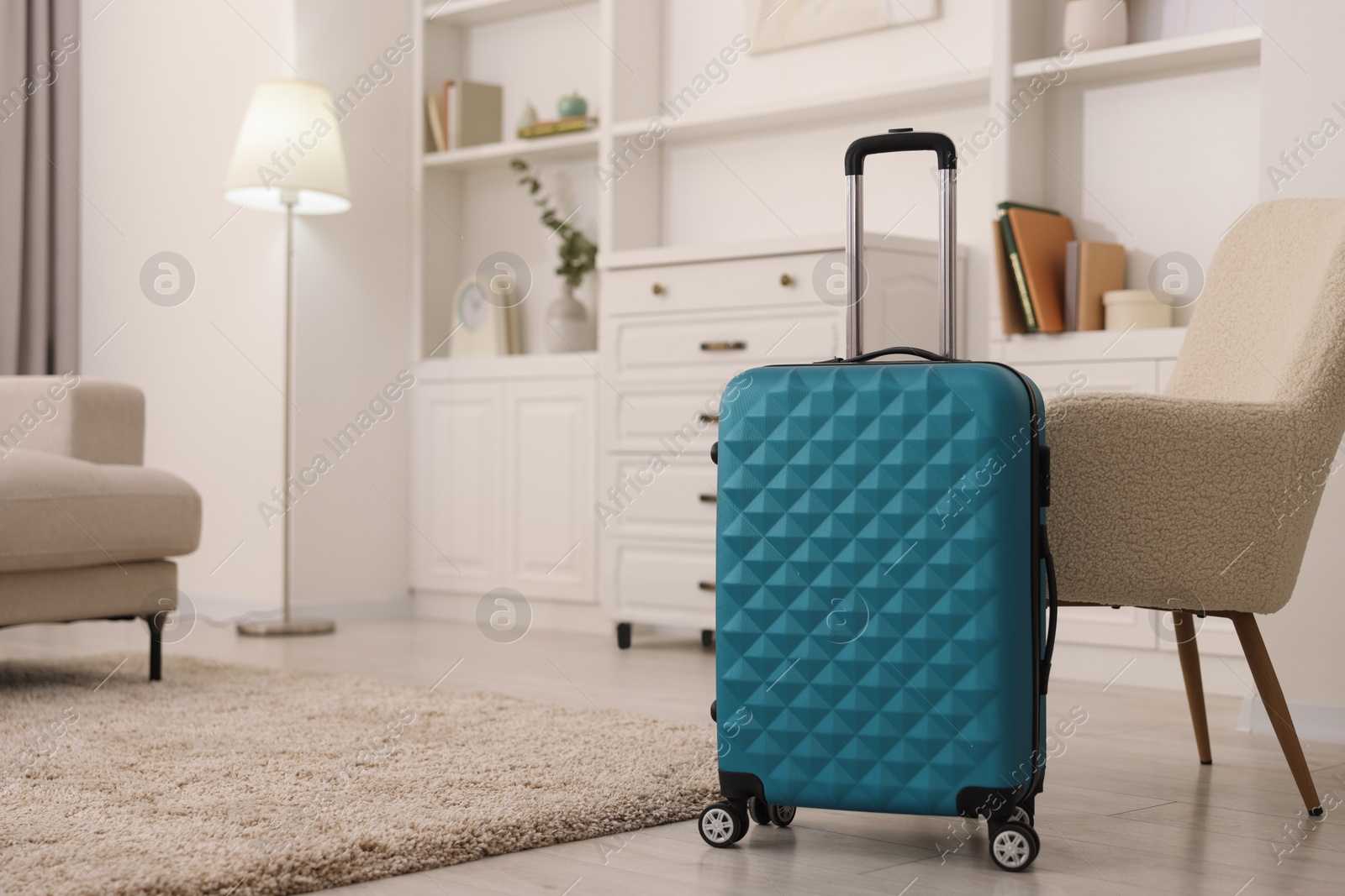 Photo of Light blue suitcase near armchair at home