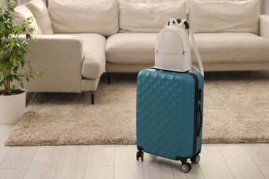 Photo of Light blue suitcase and backpack at home