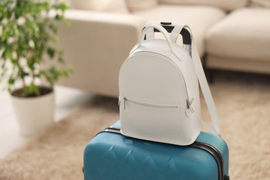 Photo of Light blue suitcase and backpack at home, space for text