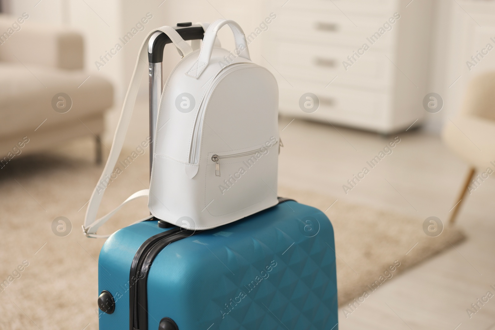 Photo of Light blue suitcase and backpack at home. Space for text