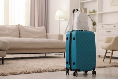 Light blue suitcase and backpack at home. Space for text