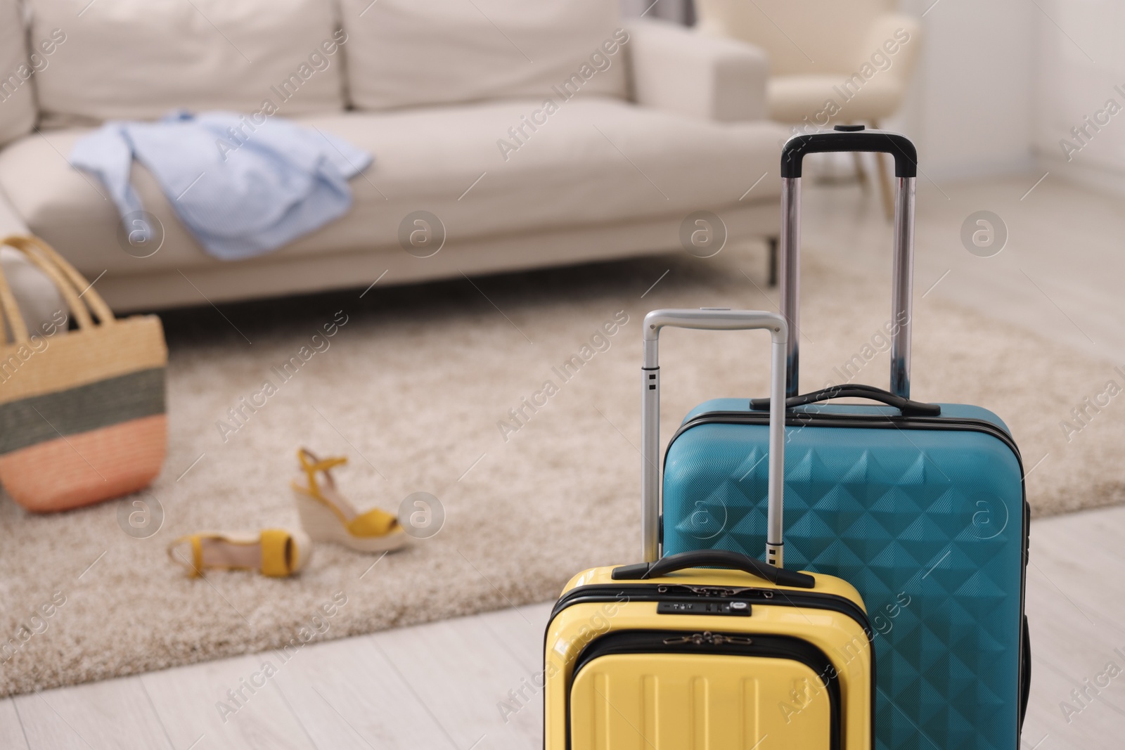 Photo of Light blue and yellow suitcases at home, space for text