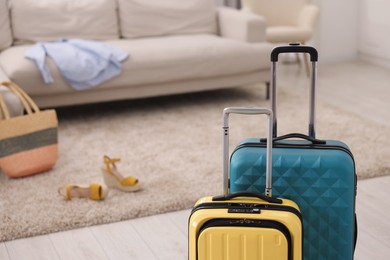 Photo of Light blue and yellow suitcases at home, space for text