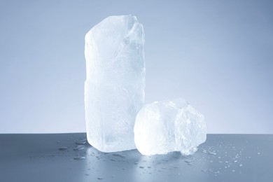 Pieces of clear ice and water drops on light grey table