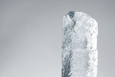 Photo of Piece of clear ice on light grey background. Space for text
