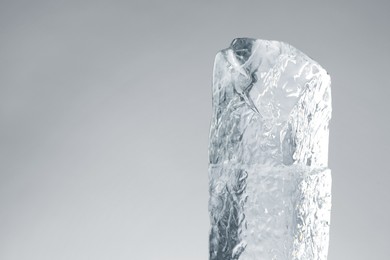 Piece of clear ice on light grey background. Space for text