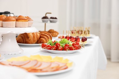 Different meals served on white table indoors, selective focus. Buffet menu