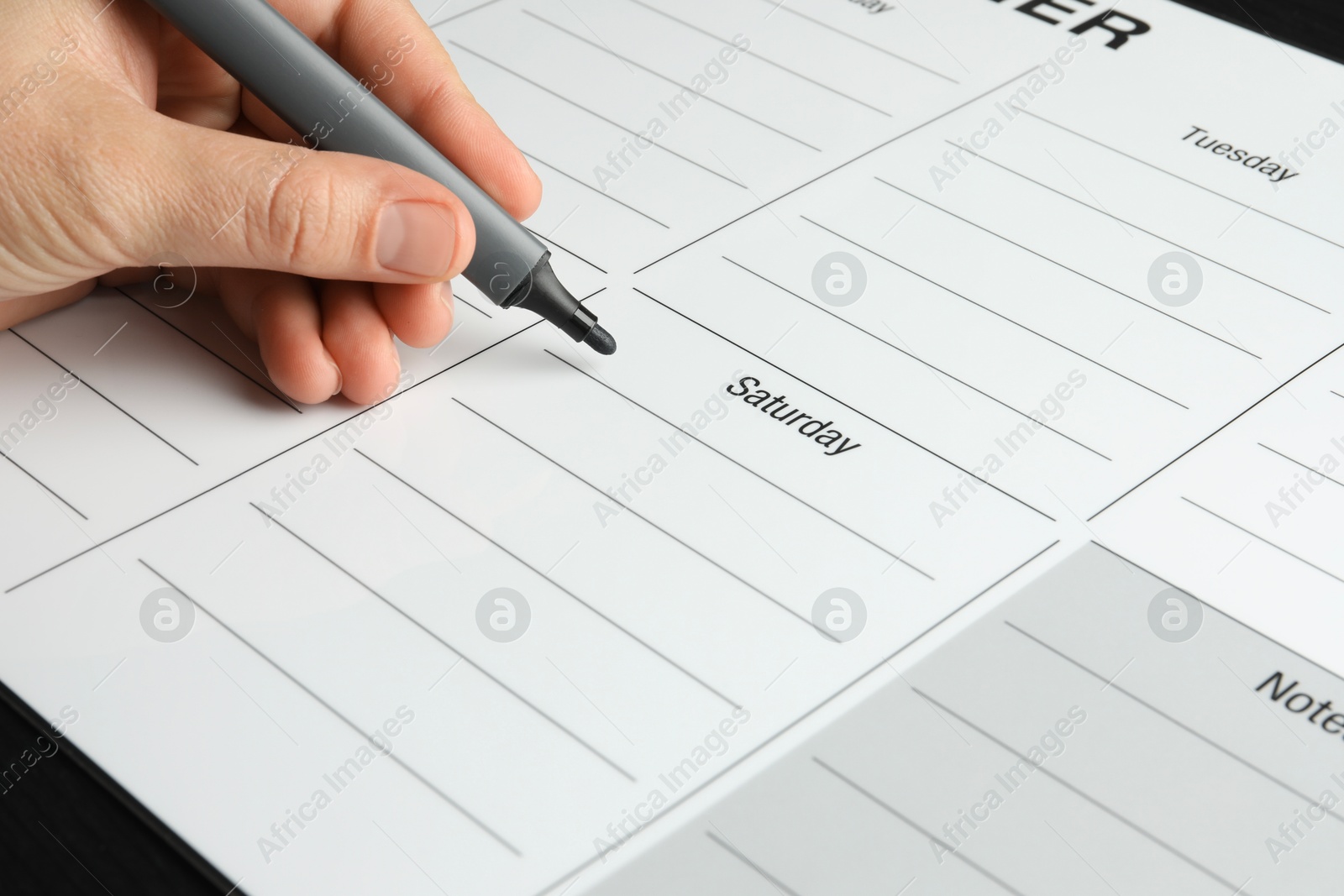 Photo of Timetable. Man making schedule using weekly planner at table, closeup