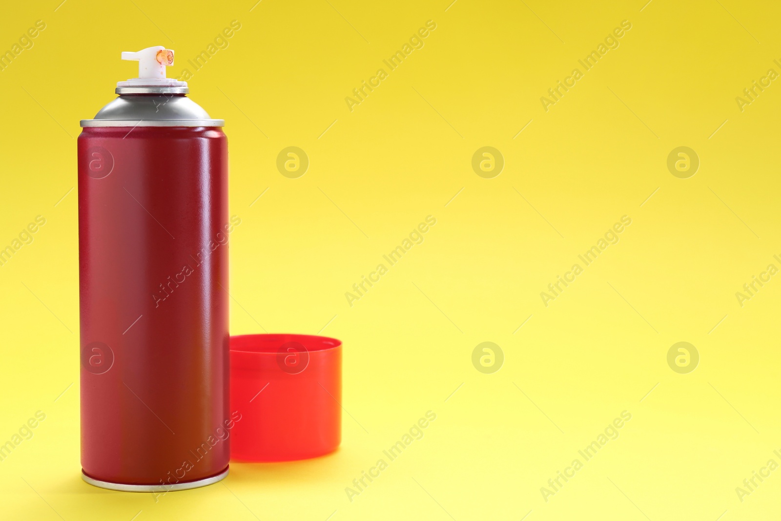 Photo of Red spray paint can on yellow background, space for text