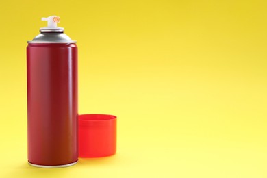 Photo of Red spray paint can on yellow background, space for text