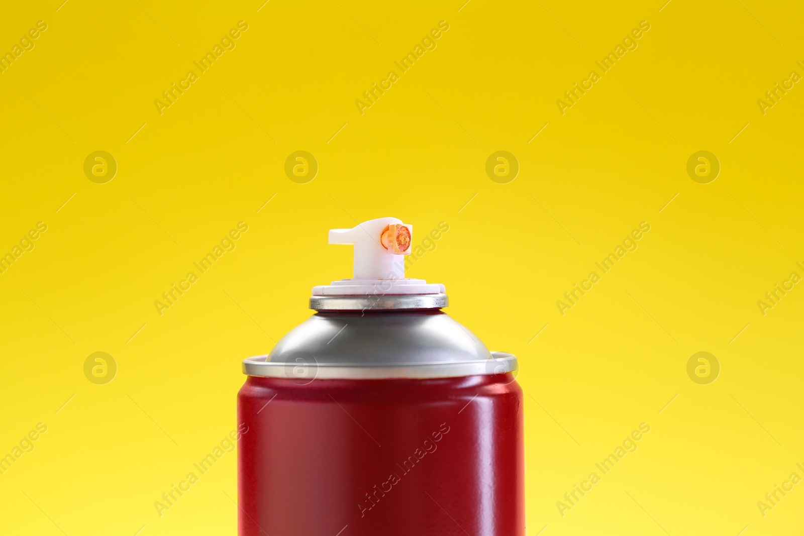 Photo of Red spray paint can on yellow background, closeup. Space for text