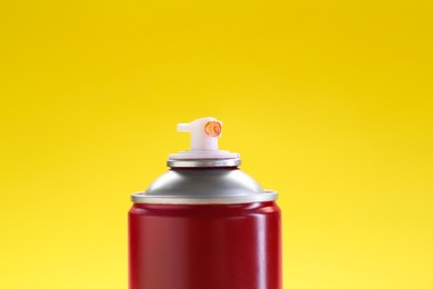 Red spray paint can on yellow background, closeup. Space for text