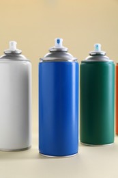 Many spray paint cans on beige background