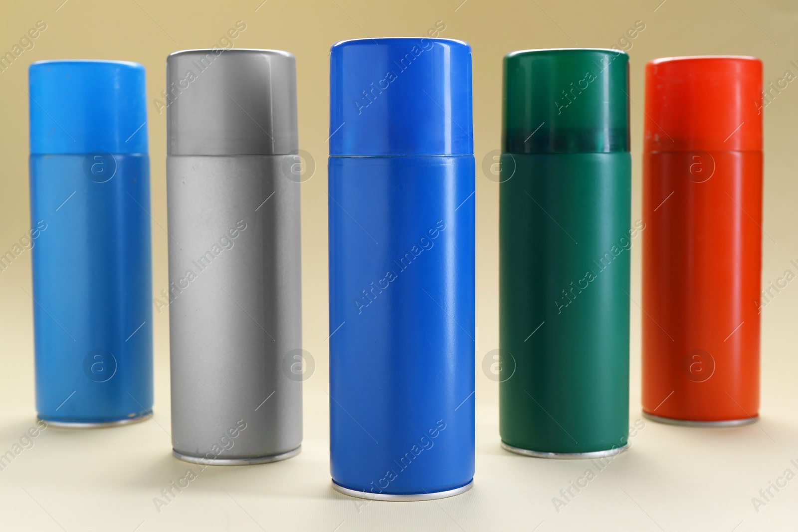 Photo of Many spray paint cans on beige background