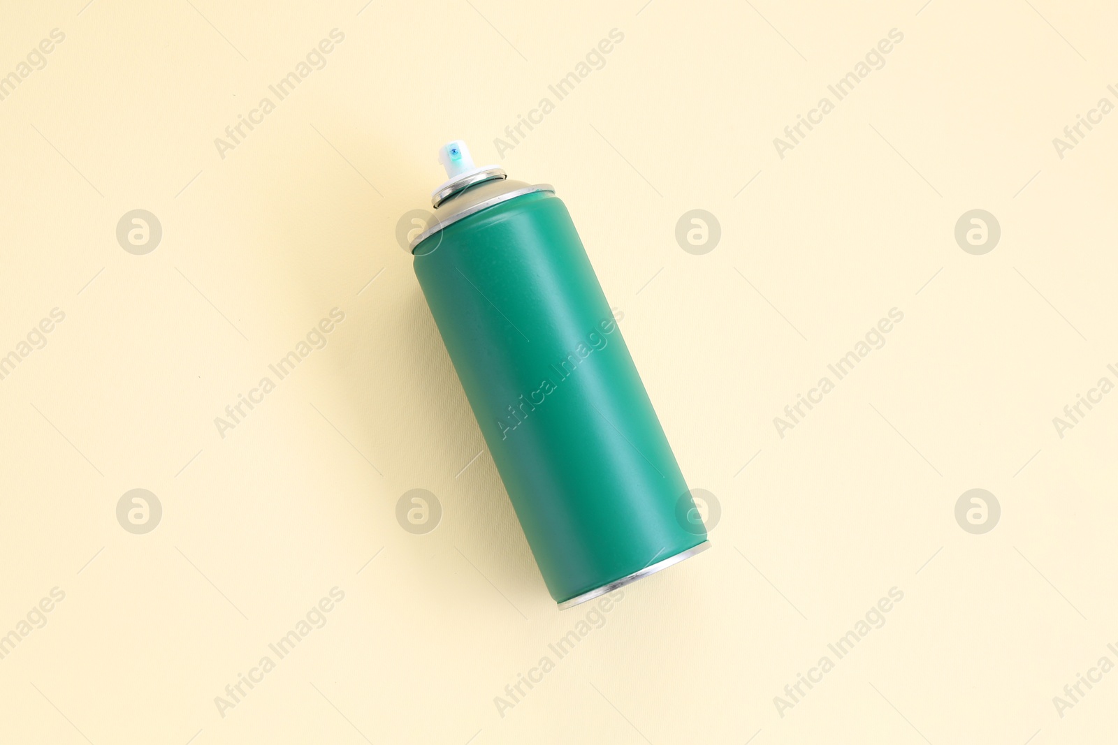 Photo of Green spray paint can on beige background, top view