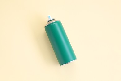 Green spray paint can on beige background, top view